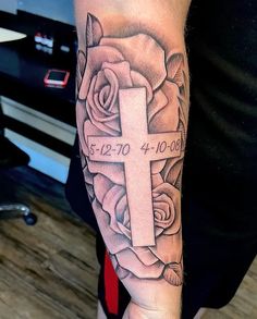 a person with a cross and roses tattoo on their arm