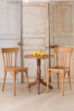 two wooden chairs and a table with fruit on it