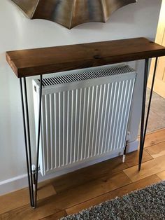 a radiator and table in front of a wall with an art piece on it