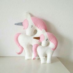 two white and pink stuffed unicorns sitting next to each other on a counter top