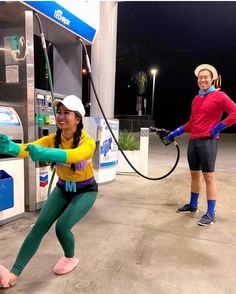 two women in green and yellow outfits are pumping gas into their pumps at night time