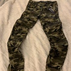 a pair of camouflage pants laying on top of a bed