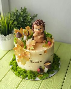 a cake with a hedge sitting on top of it next to some flowers and plants