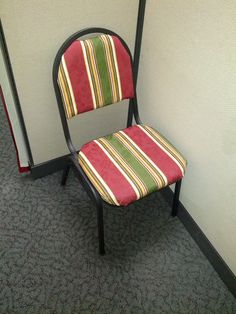 a red and green striped chair sitting next to a mirror in an office cubicle