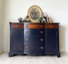 a blue dresser with pictures and plants on it's top, against a white wall