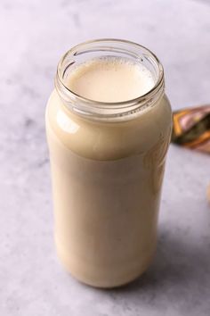 a glass jar filled with cream sitting on top of a table next to two spoons