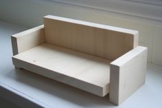 a wooden bench sitting on top of a window sill next to a white wall