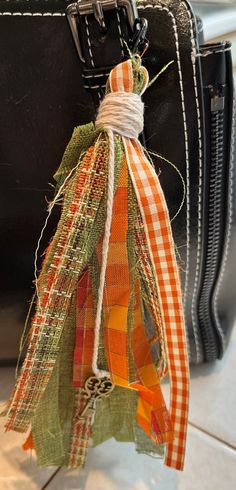 an orange and green ribbon tied to a black suitcase with a tag hanging from it