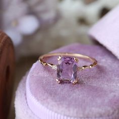 an amethorate ring sitting on top of a pink velvet cushioned box