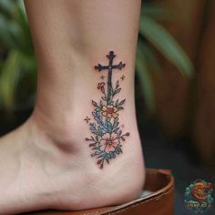 a cross with flowers on the side of her foot is shown in this tattoo design