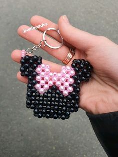 a person is holding a keychain made out of beads