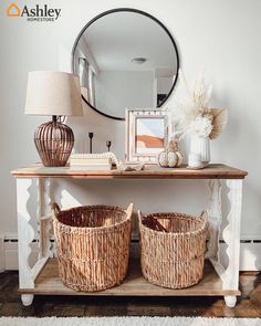 two wicker baskets sitting on top of a wooden table next to a mirror and lamp