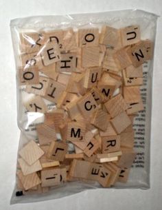 wooden scrabbles in plastic bag on white surface with words spelled by letters