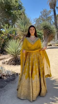 a woman in a yellow dress standing next to some trees