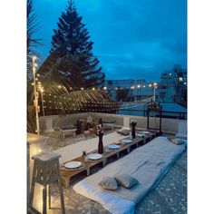 an outdoor seating area is lit up at night with string lights strung across the roof