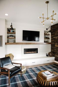 a living room with a fireplace, tv and shelves on either side of the wall