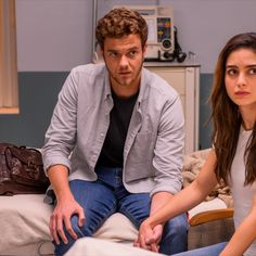 a man sitting next to a woman on top of a bed