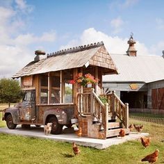 an old truck is parked in front of a barn with chickens and roosters around it