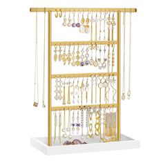 a gold jewelry rack with lots of necklaces and earrings hanging from it's sides