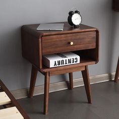 a small wooden table with a book and alarm clock sitting on it's side