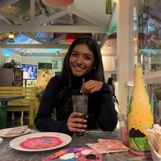 a woman sitting at a table holding a drink