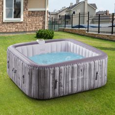 an inflatable hot tub sitting on top of a lush green field next to a house