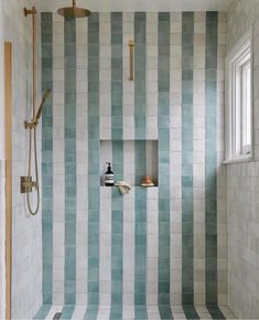 a bathroom with blue and white tiles on the walls, shower head, and hand held faucet