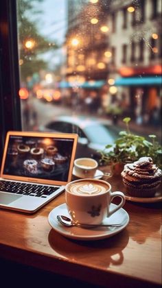 a laptop computer sitting on top of a wooden table next to a cup of coffee