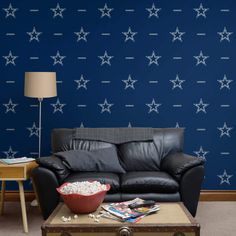 a living room with a black leather couch and blue star wallpaper on the walls