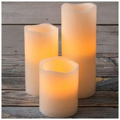 three lit candles sitting on top of a wooden table