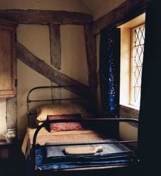 an old fashioned bed in a room with wooden walls and beams on the ceiling, next to a window