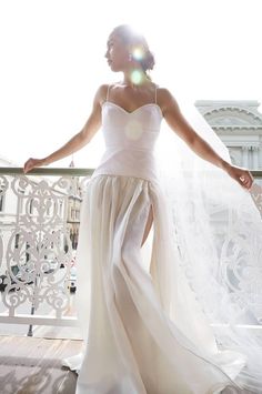 a woman in a white dress is standing on a balcony with her arms spread out