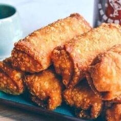 some fried food on a blue plate next to a cup of coffee