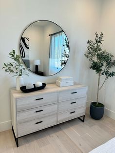 there is a mirror on the wall next to a dresser and a potted plant