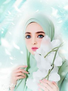 a woman wearing a hijab holding a white flower in her hand and looking at the camera