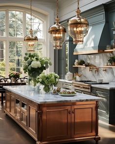 a large kitchen with marble counter tops and gold pendant lights hanging from the ceiling over the island