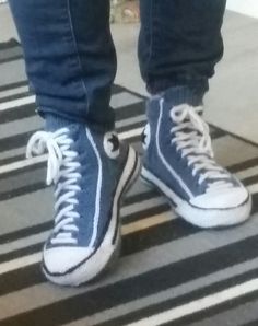 a person standing on top of a black and white striped rug wearing blue converse shoes