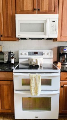 a white stove top oven sitting inside of a kitchen next to wooden cupboards and counter tops