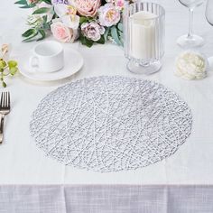 the table is set with white linens and silverware, flowers, candles, and napkins