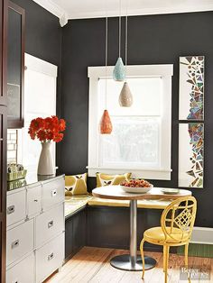 a kitchen with black walls and yellow chairs in the corner, along with white cabinets