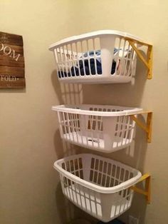 three white laundry baskets stacked on top of each other next to a wall mounted sign