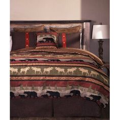 a bed with a brown and red blanket on top of it next to a lamp