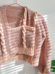 a pink sweater hanging on a white wall