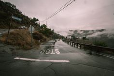 an empty road with the word slow painted on it in front of mountains and clouds