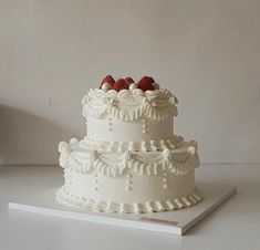 a three tiered white cake with strawberries on top