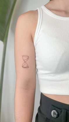 a woman's arm with a tattoo on it that has an hourglass in the sand