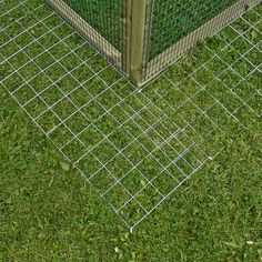 a dog is standing in the grass next to a fence with a box on it