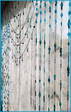 a curtain with beads hanging from it's side in front of a blue frame