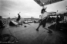 a woman is dancing on the stage with her hair blowing in the wind while other people watch