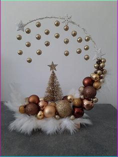 a christmas tree surrounded by ornaments on a table with a white wall in the background